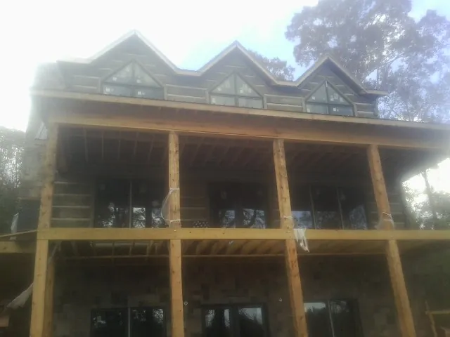 Dormers and porch framing on a large log home under construction — Roof Coating work by our crew in Brazoria