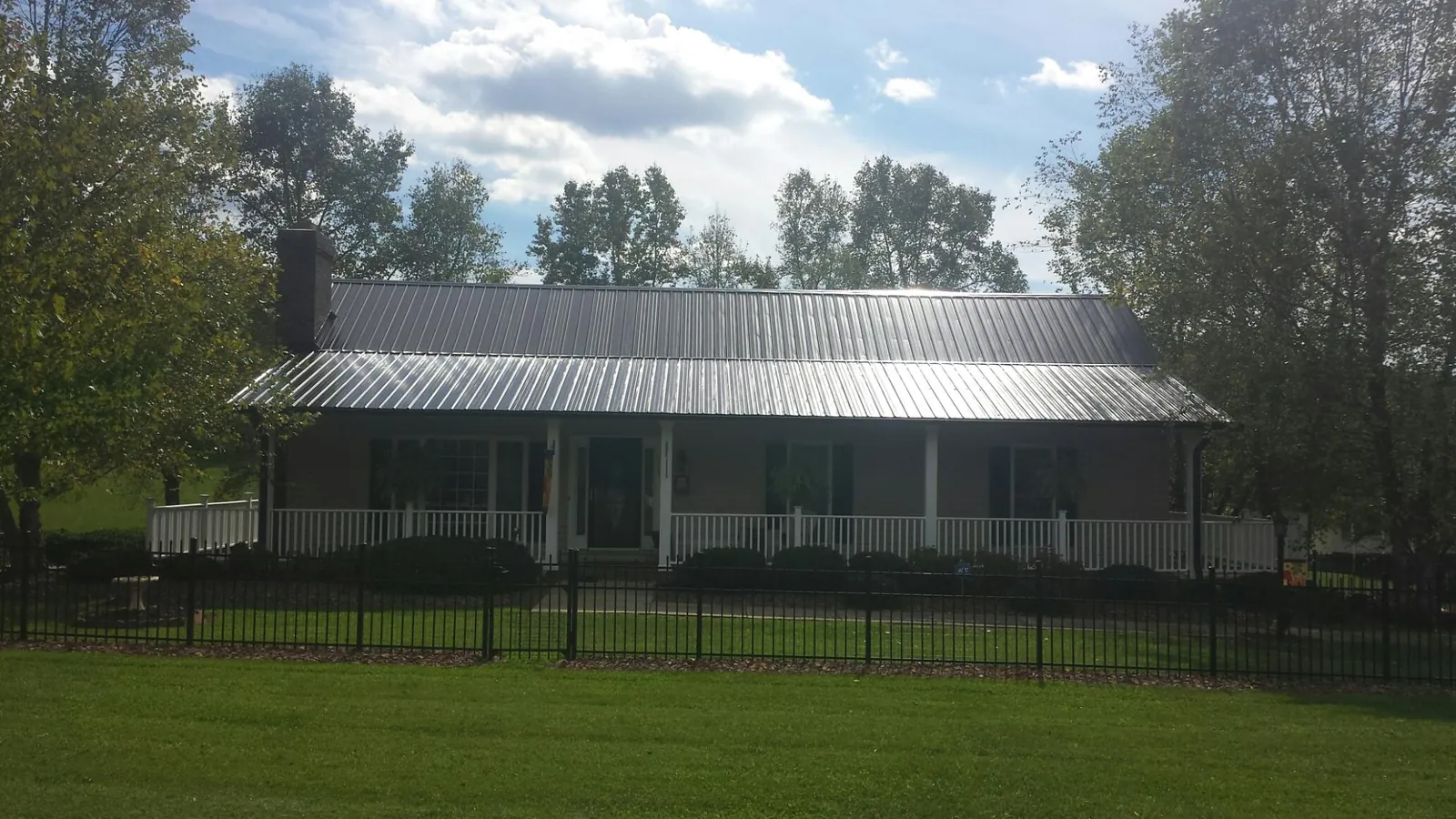 Gray metal roof on a brick ranch with a full width front porch — Gutter Guard Installation work by our crew in Brazoria
